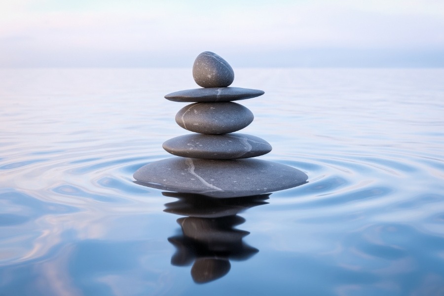 A structure of five rocks on top of calm water with small ripples.